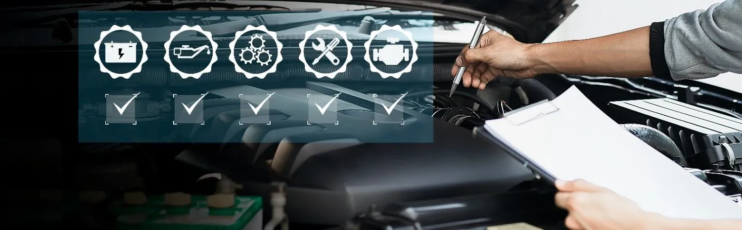 Mechanic reviewing a checklist beside an open engine bay